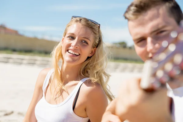 Jovem casal tocando guitarra na praia no amor — Fotografia de Stock