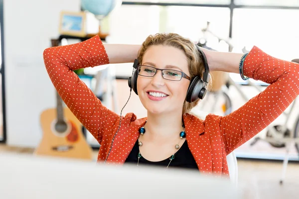 Junge Frau mit Kopfhörern im Büro — Stockfoto