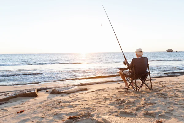 Uomo anziano pesca sul lato mare — Foto Stock