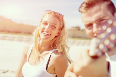 Genç çift aşık sahilde gitar çalmak