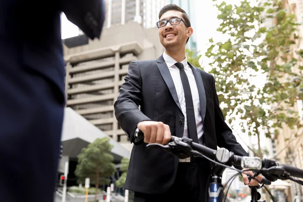 Два молодых бизнесмена с велосипедом в центре города — стоковое фото