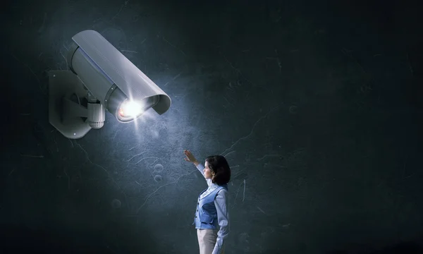 Geschäftsfrau in Zimmer unter Überwachungskamera unkenntlich gemacht — Stockbild Kamera behält Frau im Auge. Gemischte Medien — Stockfoto