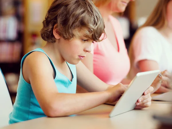 Niño en la biblioteca con el ordenador — Foto de Stock