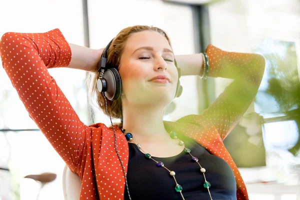 Jeune femme au bureau avec écouteurs — Photo