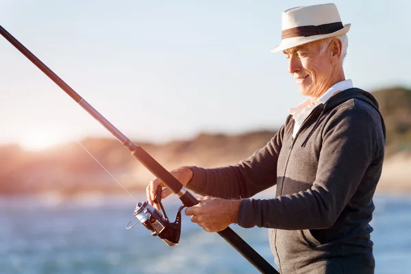 Senior man fishing at sea side — Stock Photo, Image