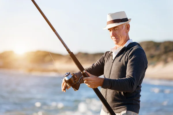 Senior man fishing at sea side — Stock Photo, Image