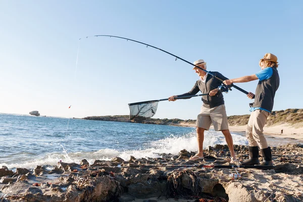 Uomo anziano pesca con suo nipote — Foto Stock