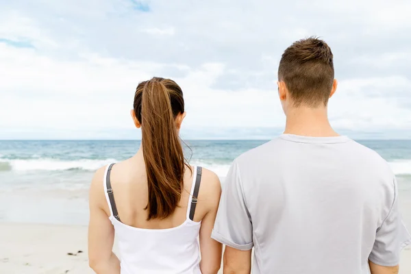 Νεαρό ζευγάρι ψάχνει στοχαστικό ενώ στέκεται δίπλα στην άλλη στην παραλία — Φωτογραφία Αρχείου