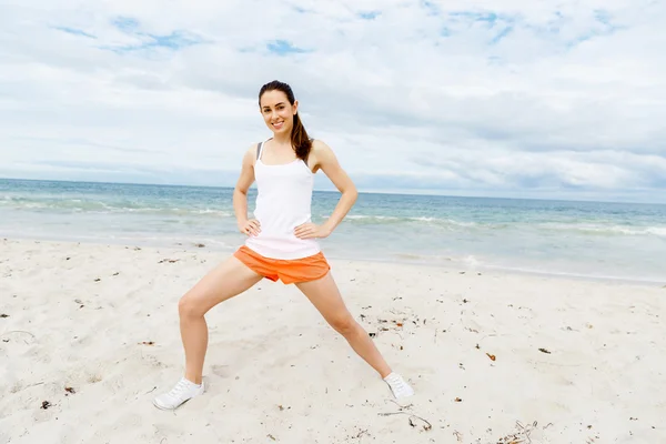 Mujer joven entrenando en la playa afuera — Foto de Stock