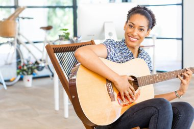 Gitar ile iş içinde oturan Afro-Amerikan ofis çalışanı gülümseyen portresi
