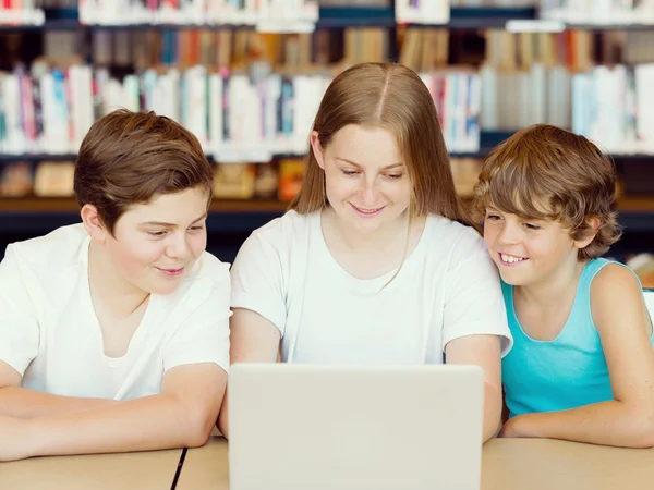 Drie kinderen in bibliotheek — Stockfoto