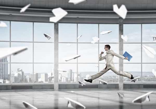 Jumping businessman in office . Mixed media — Stock Photo, Image