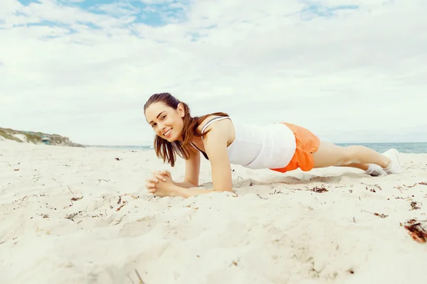 Mujer joven entrenando en la playa afuera — Foto de Stock