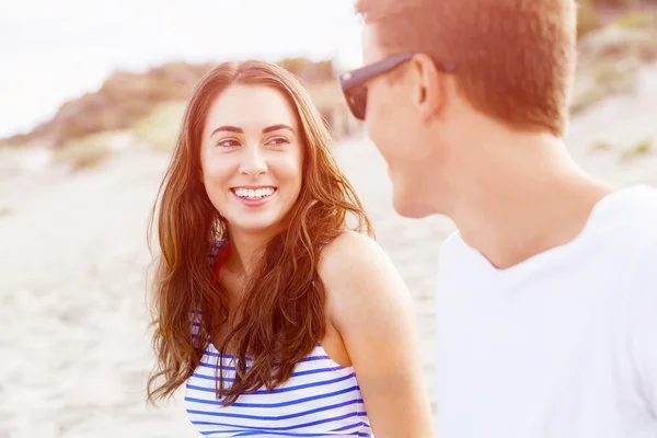 Romantische jonge paar zittend op het strand — Stockfoto