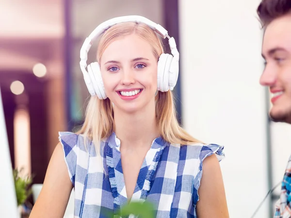 Jovem mulher ouvindo a música enquanto trabalhava em um computador — Fotografia de Stock