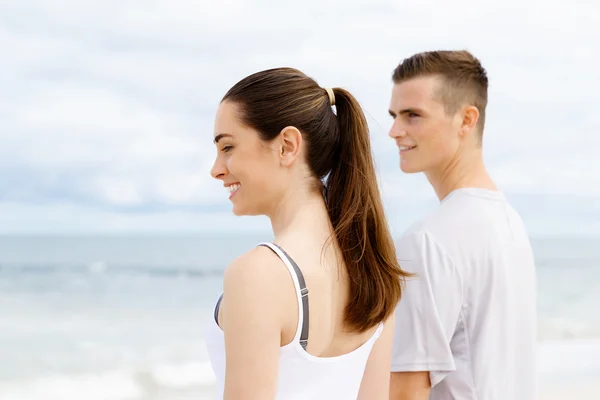 Pareja joven buscando reflexivo mientras están de pie uno al lado del otro en la playa —  Fotos de Stock