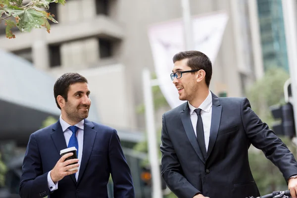 Deux jeunes hommes d'affaires avec un vélo dans le centre-ville — Photo