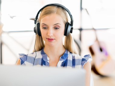 Kulaklıklar ile ofiste çalışan genç kadın