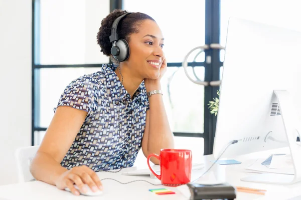 Portrait of smiling afro-american office worker sitting in offfice with headphones — Stock Photo, Image