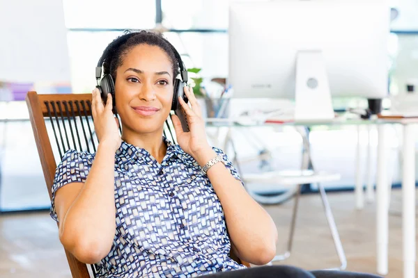 Afro-Amerikan ofis çalışanı müydü kulaklık ile oturan gülümseyen portresi — Stok fotoğraf