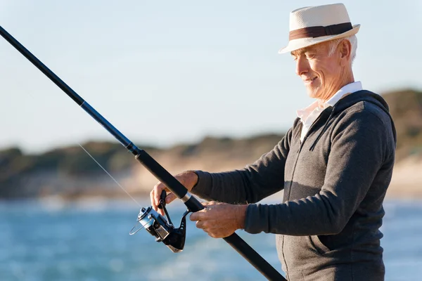 Starszy człowiek, wędkowanie na morzu po stronie — Zdjęcie stockowe