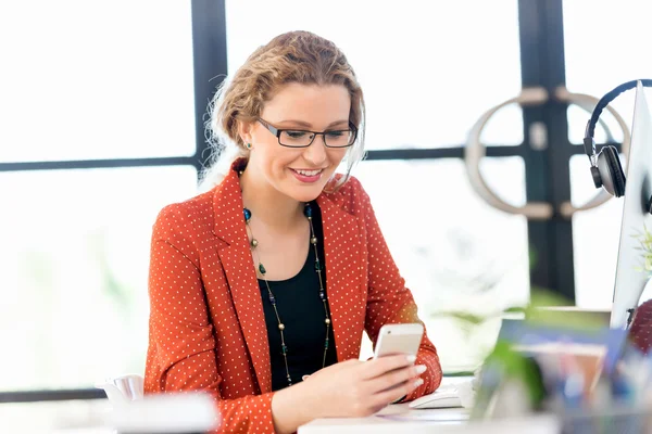 Young woman holding mobile phone in office — Stock Photo, Image