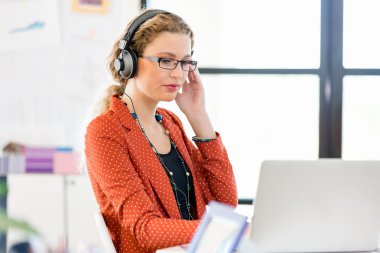 Genç kadın bir bilgisayarda çalışırken müzik