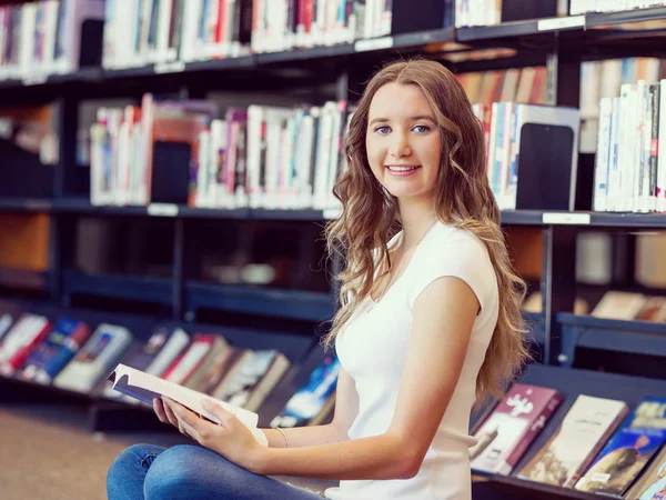 快乐的女学生在图书馆拿着书 — 图库照片