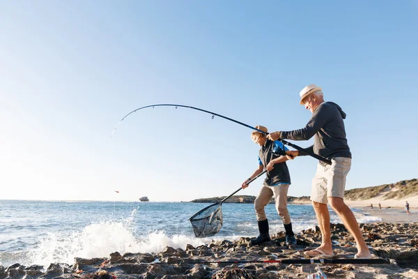 Uomo anziano pesca con suo nipote — Foto Stock