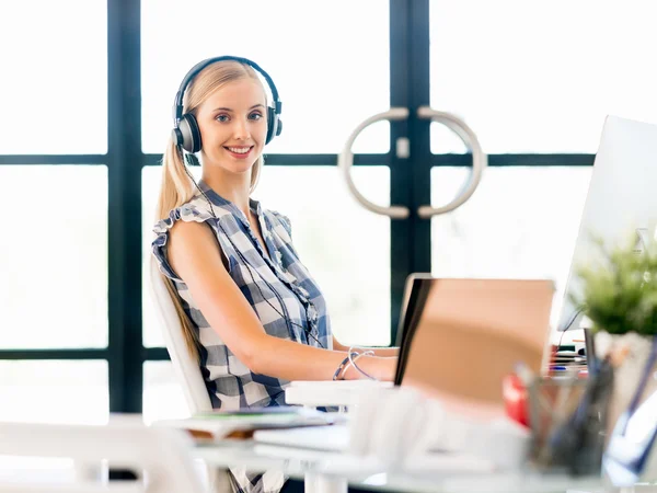 Junge Frau hört Musik, während sie am Computer arbeitet — Stockfoto