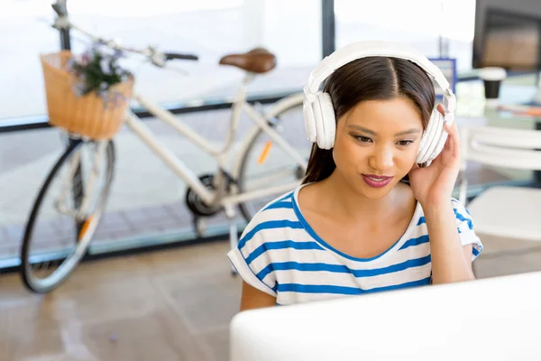 Young woman in office with headphones — Stock Photo, Image