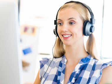 Kulaklıklar ile ofiste çalışan genç kadın