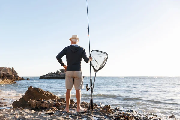 Uomo anziano pesca sul lato mare — Foto Stock