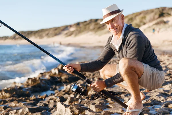 Senior man fishing at sea side — Stock Photo, Image