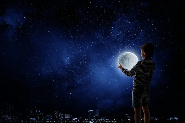 Menino segurando lua à noite — Fotografia de Stock