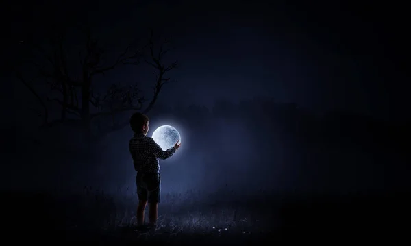 Niño sosteniendo la luna por la noche — Foto de Stock