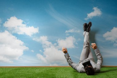 İşadamı bacaklarını duvara dayayıp rahatlıyor.