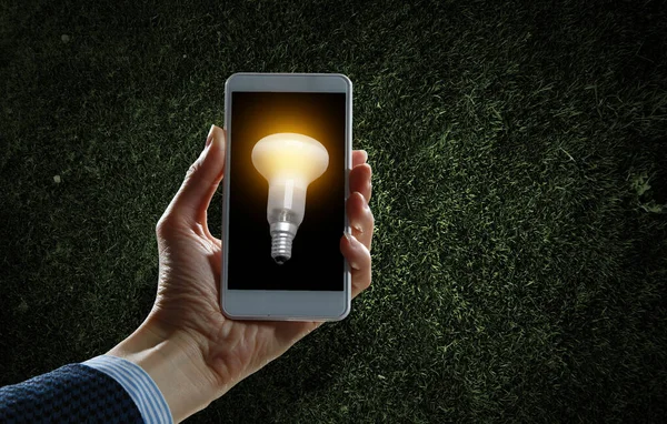 Glühbirne auf dem Handy-Bildschirm — Stockfoto