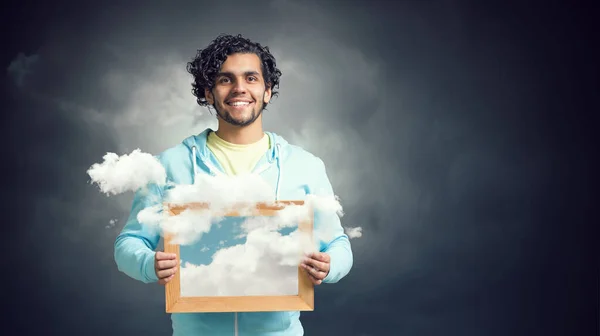 Hombre sosteniendo marco con cielo azul y nubes — Foto de Stock