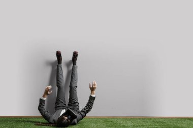 İşadamı bacaklarını duvara dayayıp rahatlıyor.