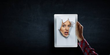 Kadın yüzü kağıttaki delikten geçiyor.