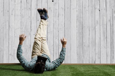 İşadamı bacaklarını duvara dayayıp rahatlıyor.