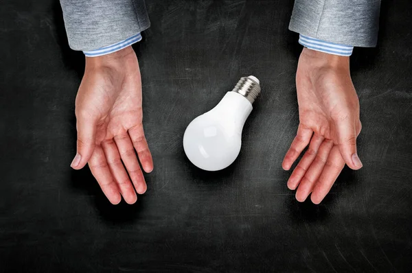 Light bulb between hands . Mixed media — Stock Photo, Image