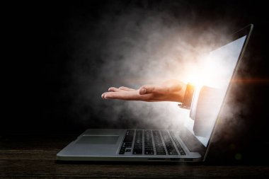 Aydınlatılmış ekranlı dizüstü bilgisayar ve açık avuç içi insan eli