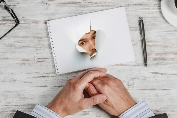 Männliches Gesicht durch das Loch in Papier — Stockfoto