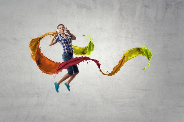 Woman wearing headphones jumping . Mixed media — Stock Photo, Image