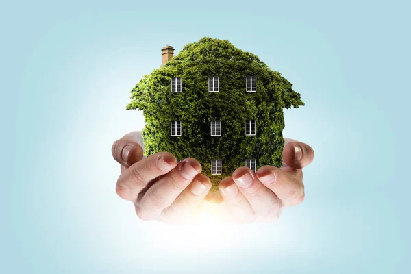Χέρι που κρατάει πράσινο σπίτι. Μεικτά μέσα — Φωτογραφία Αρχείου
