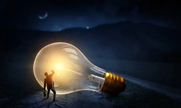 Huge light bulb glowing in the darkness — Stock Photo, Image