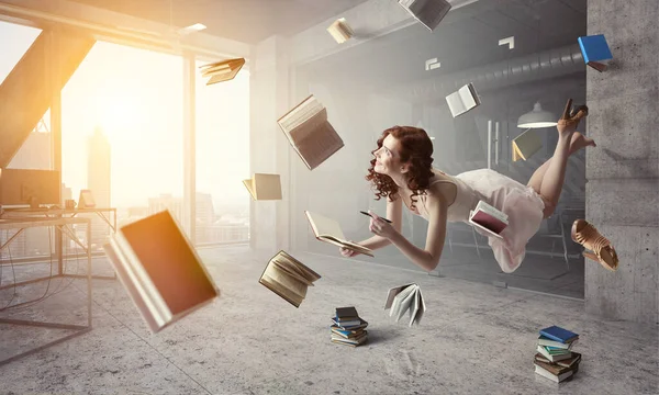 Молодая женщина левитирует во время чтения книги — стоковое фото