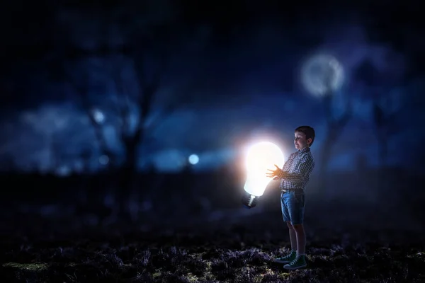 Niño con una bombilla brillante — Foto de Stock